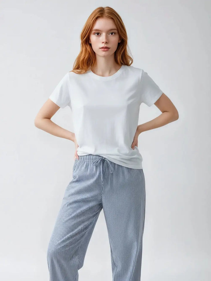 Person wearing a white t-shirt and blue striped pants on a light gray background