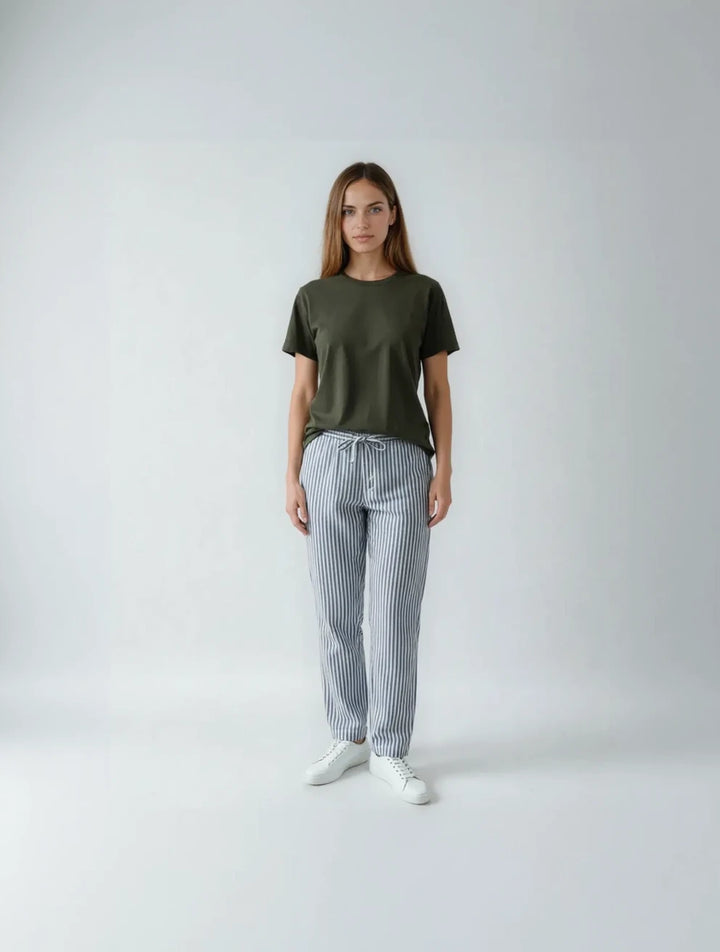 Woman wearing an olive green t-shirt and striped pants on a white background