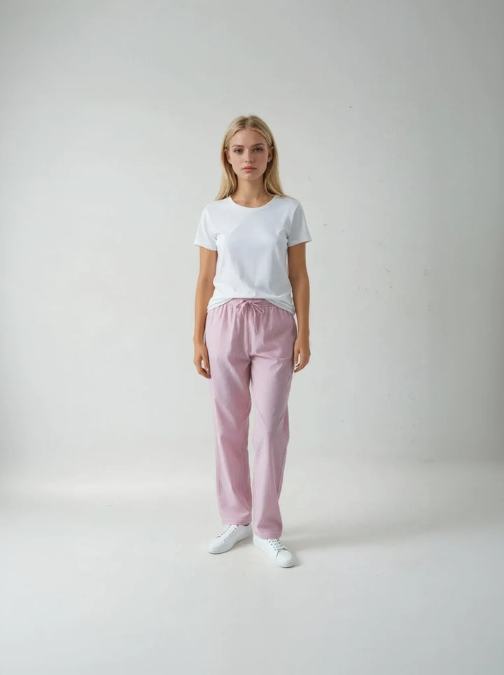 Woman wearing a white t-shirt and pink pants on a plain background