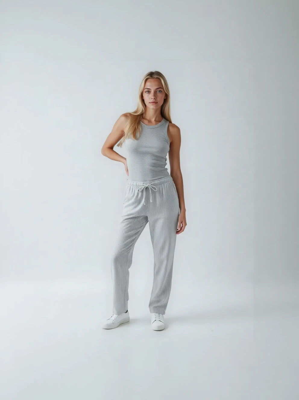 Woman wearing a gray tank top and matching pants on a white background