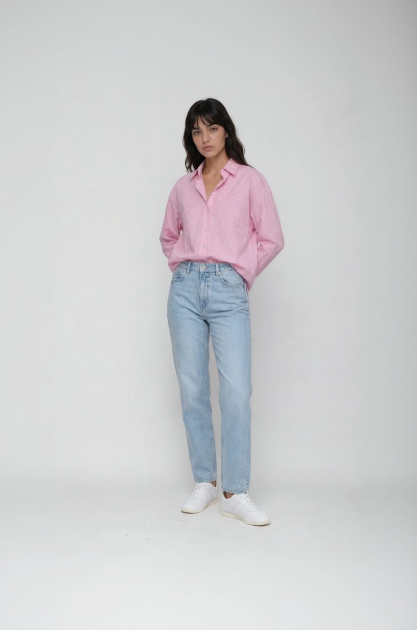 Woman wearing a pink shirt, light blue jeans, and white sneakers on a white background